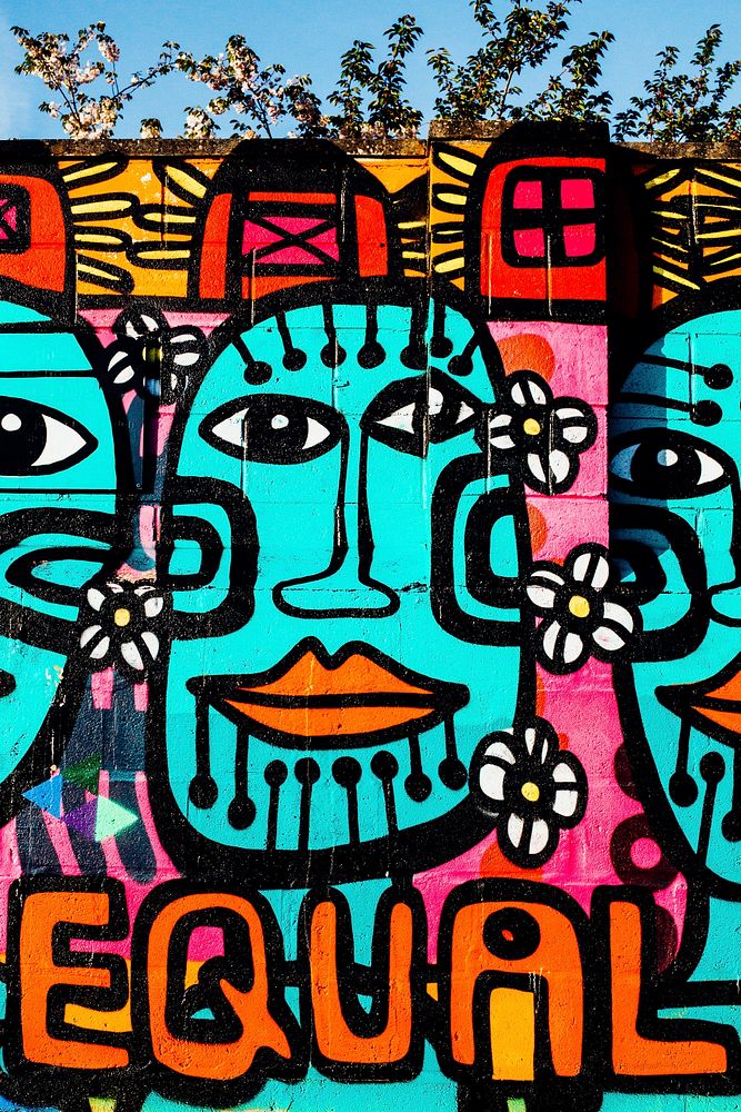 Brightly colored urban graffiti mural artwork on wall with equal text and tribal faces, location unknown -  21 April 2017.…