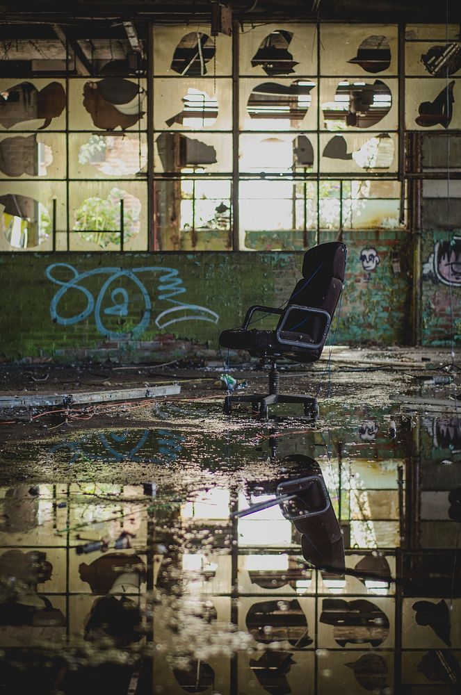 Abandoned urban warehouse with chair and water reflection with graffiti tags on wall, Sheffield United Kingdom. Original…