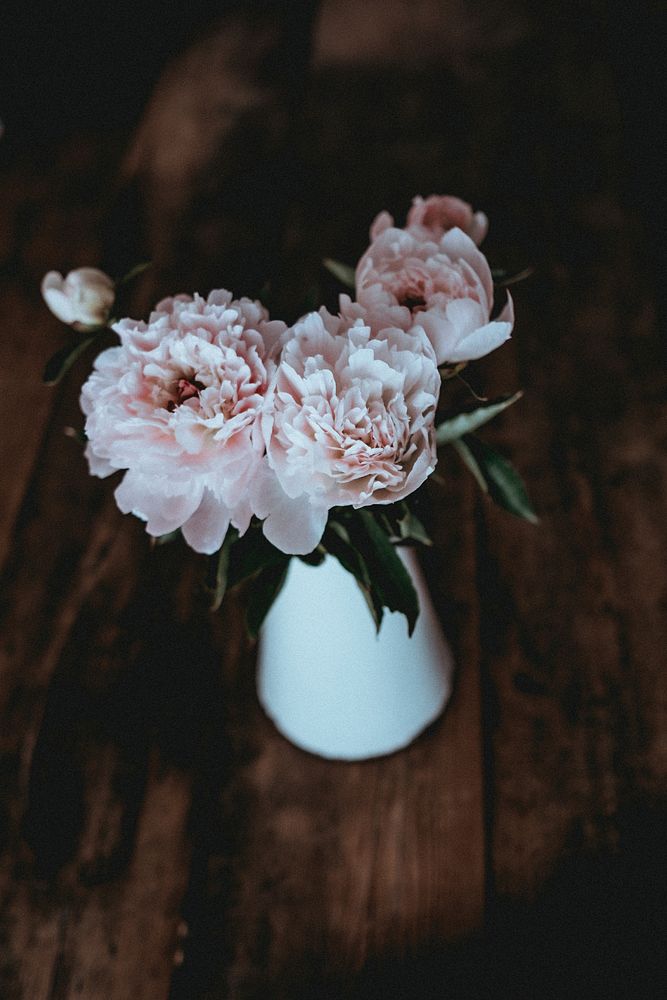 Pink carnation flowers in a vase on wooden table.Original public domain image from Wikimedia Commons