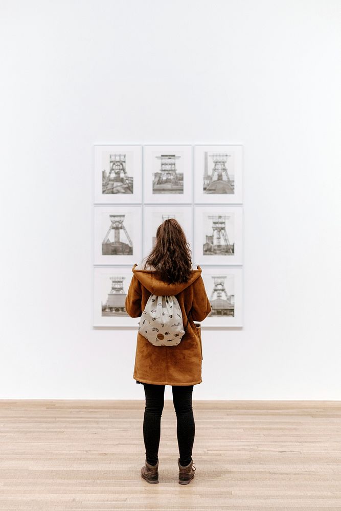 Young woman with brown hooded jacket and backpack view artwork on white background at Tate Modern. Original public domain…