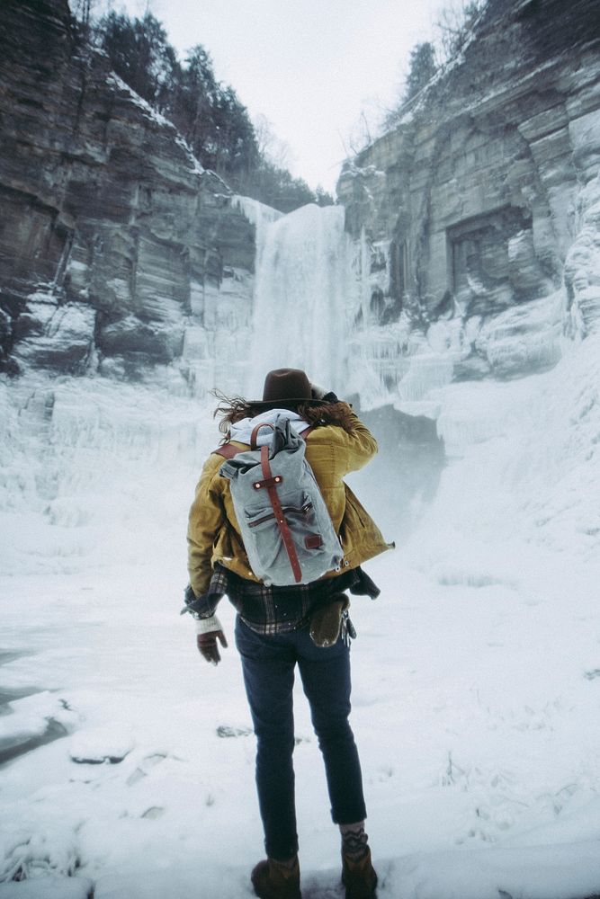 A hiker staring at a winter waterfall from the bottom of a mountain in Ithaca, New York. Original public domain image from…