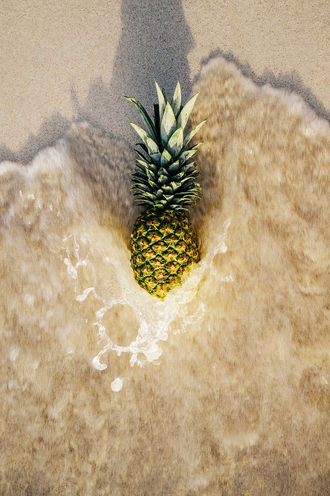 Pineapple on the beach being swept by the tide. Original public domain image from Wikimedia Commons