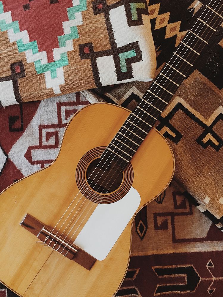 An acoustic guitar and tribal patterned pillows. Original public domain image from Wikimedia Commons