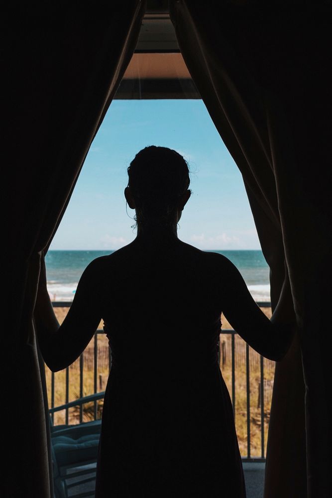Silhouette of the person looking through balcony curtains on the Ocean Isle Beach coast. Original public domain image from…