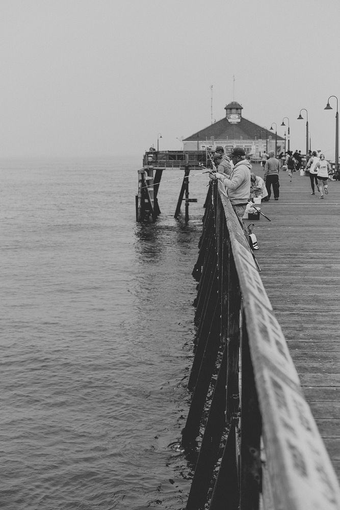 Black and white photograph of people fishing on a pier at Imperial Beach. Original public domain image from Wikimedia Commons