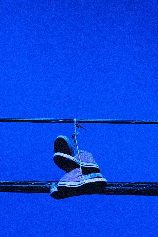 Sneakers hanging from power lines, neon blue summer aesthetic