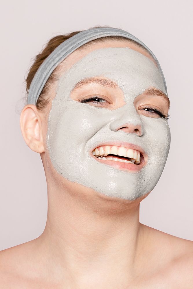 Happy woman in clay facial mask, spa treatment