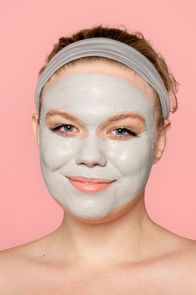 Happy woman in clay facial mask, spa treatment