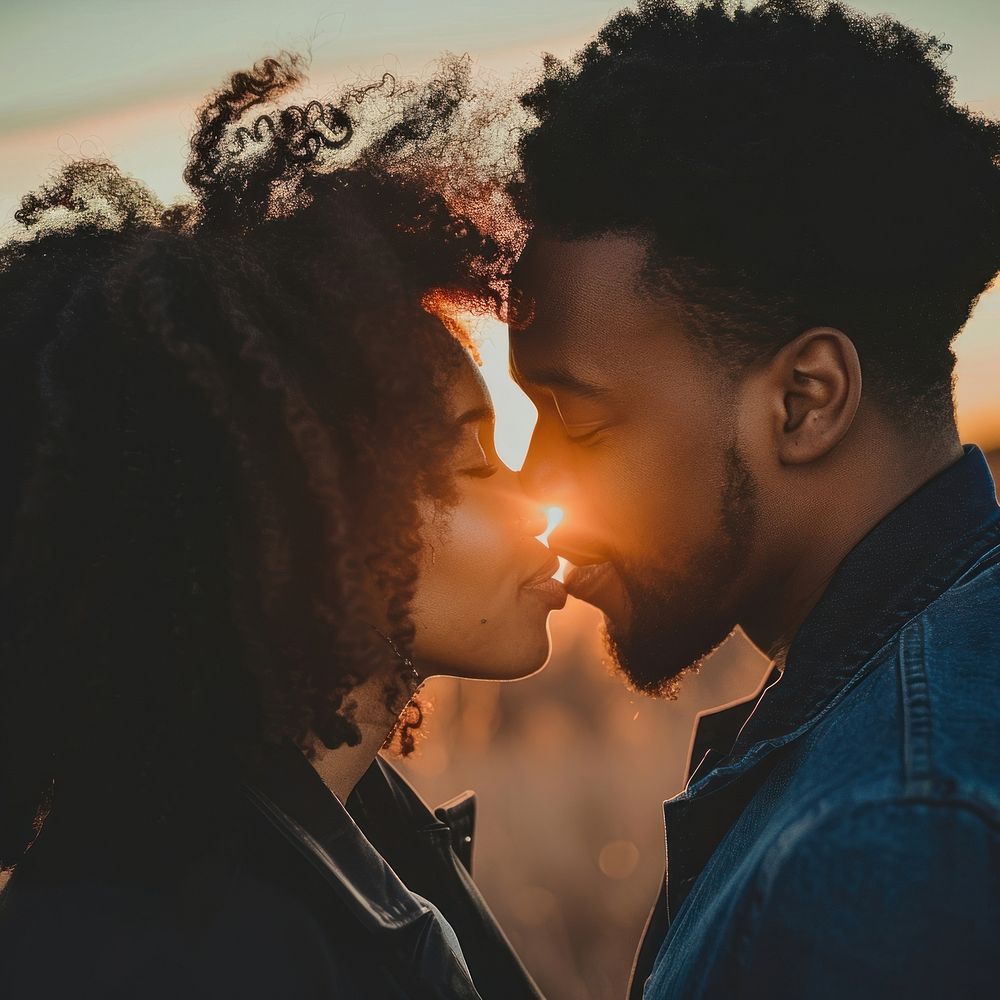 Black couple sharing a kiss portrait kissing sunset.