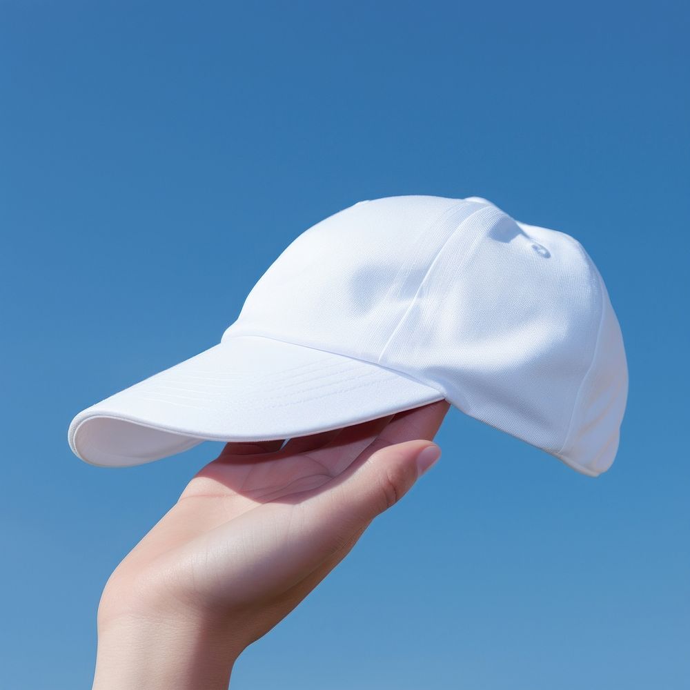 Close up hand upper white cap blue sky headwear.