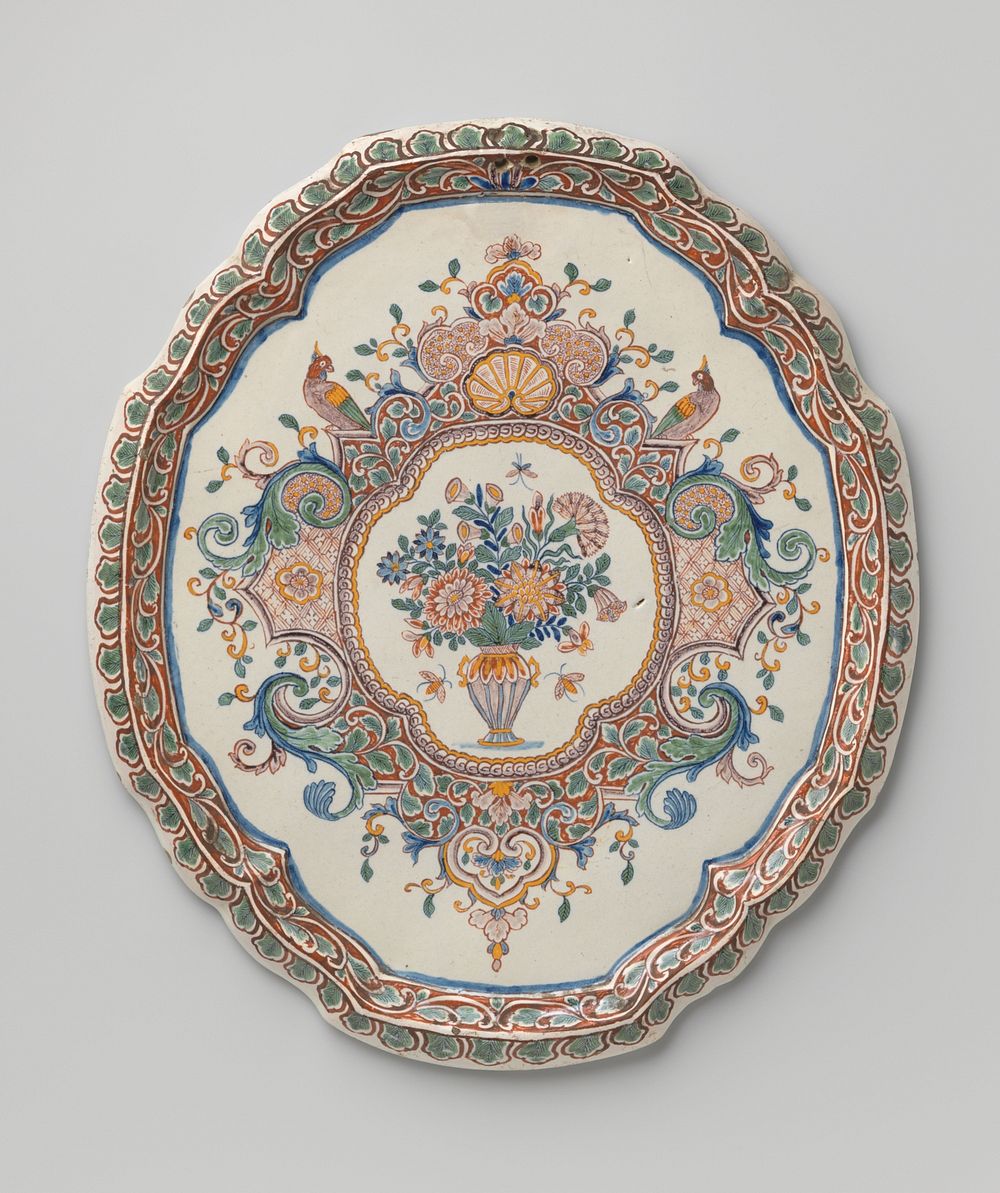 Plaat, ovaal met uitgeschulpte rand, veelkleurig beschilderd met een medaillon waarin een bloemenvaas tussen lambrequins (c.…