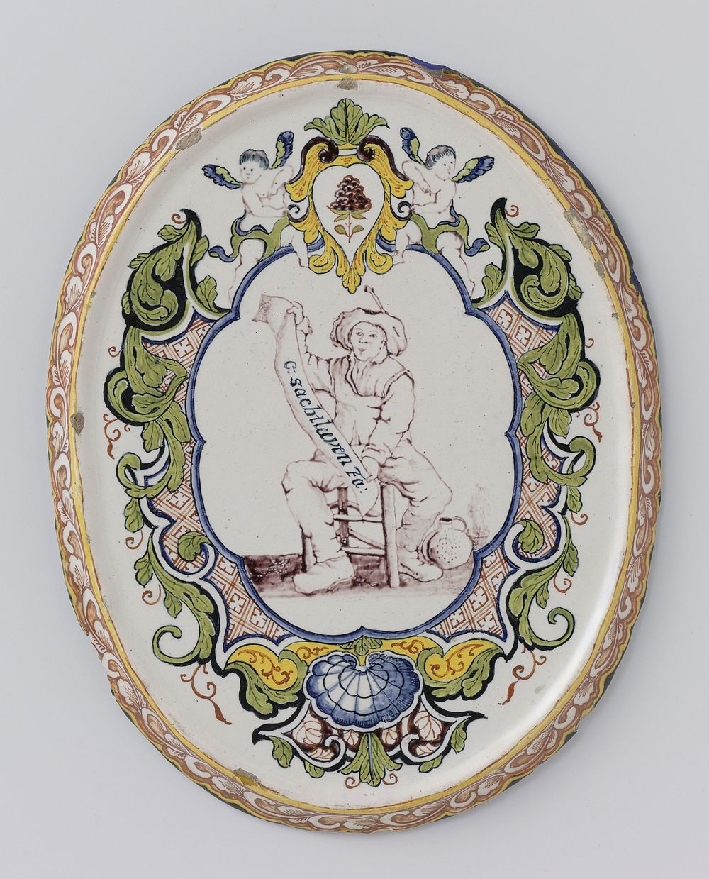 Plaat, ovaal, veelkleurig beschilderd met een boer zittend binnen lambrequinrand en onderschrift: G.SACHTLEEVEN (c. 1750 -…