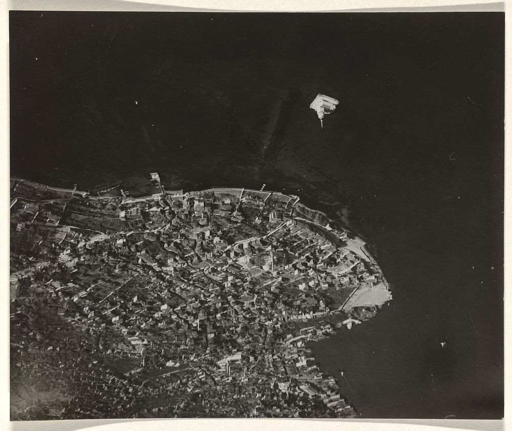 Luchtfoto in zwart-wit van een stad of dorp, gelegen aan het water, met een schiereiland en installatie (1930 - 1975) by…