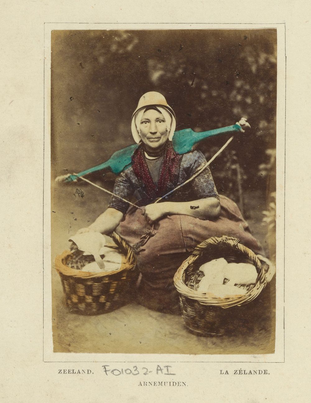 Portret van een onbekende vrouw met juk en manden met vermoedelijk mutsjes, in klederdracht van Arnemuiden, Zeeland (1860 -…