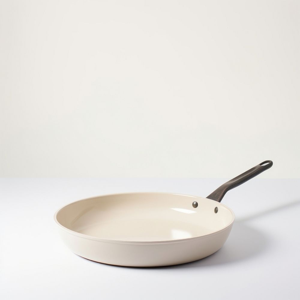 A beige ceramic pan cookware white background silverware.