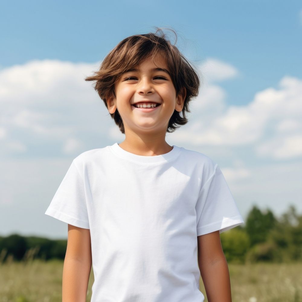 Boy wearing white t-shirt laughing outdoors smiling.
