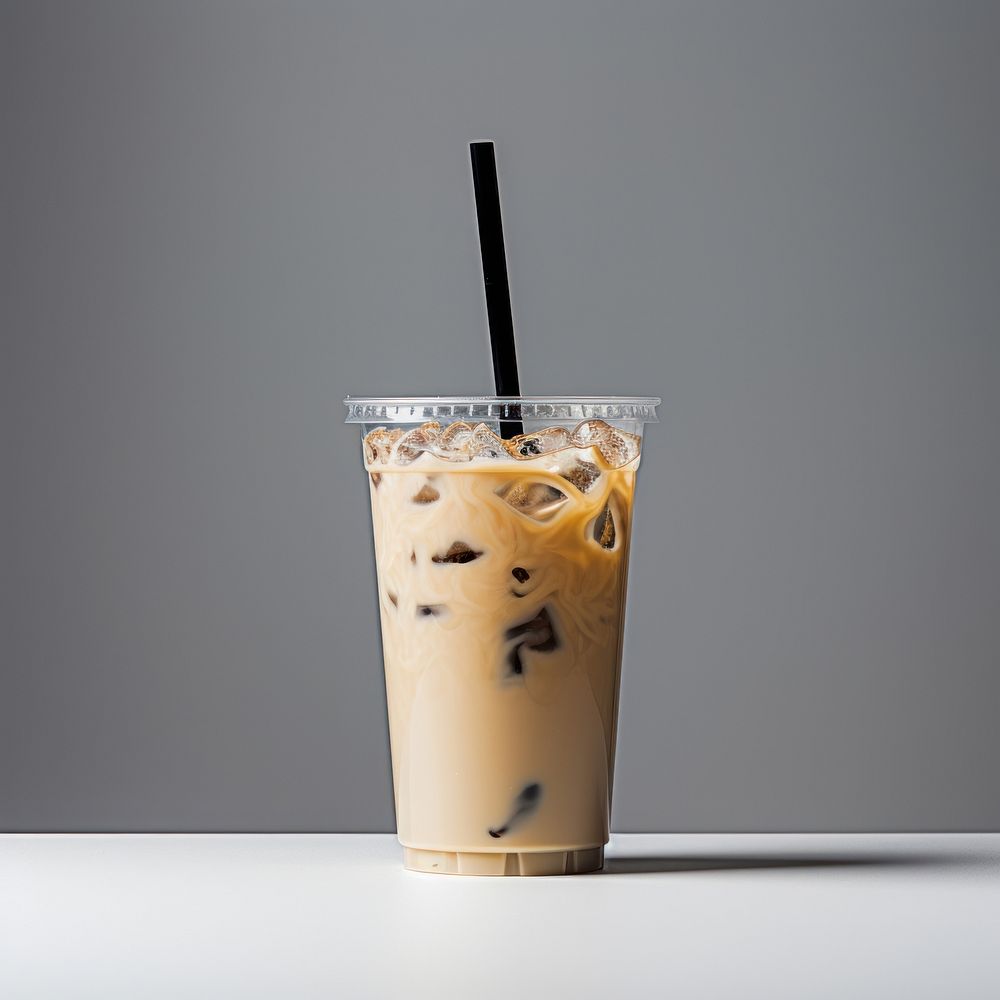 A plastic disposable ice coffee glass with straw and blank white label drink milk refreshment.