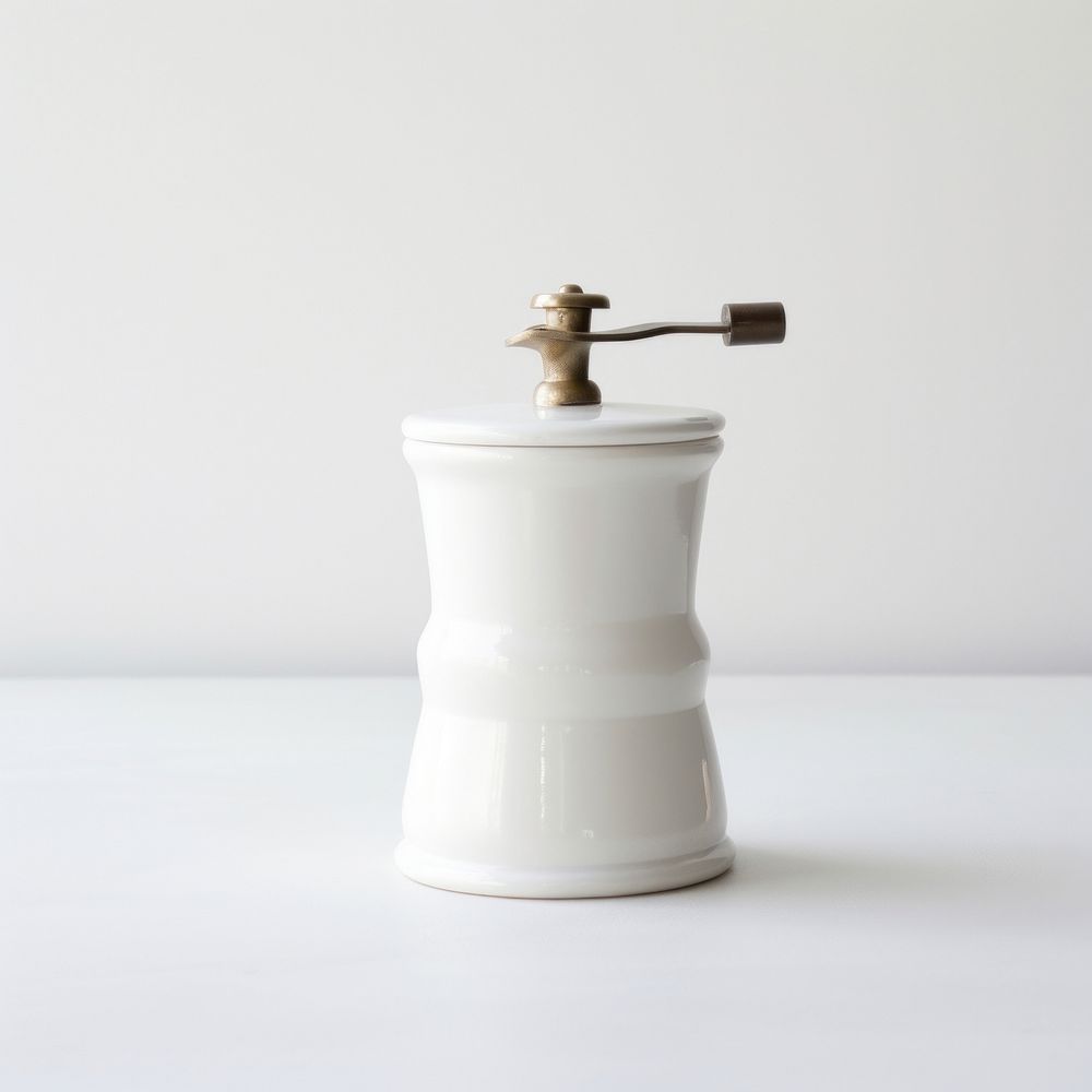 A white minimal ceramic coffee grinder white background porcelain cylinder.