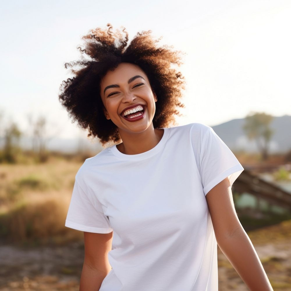 Woman wearing white t-shirt laughing outdoors smiling.