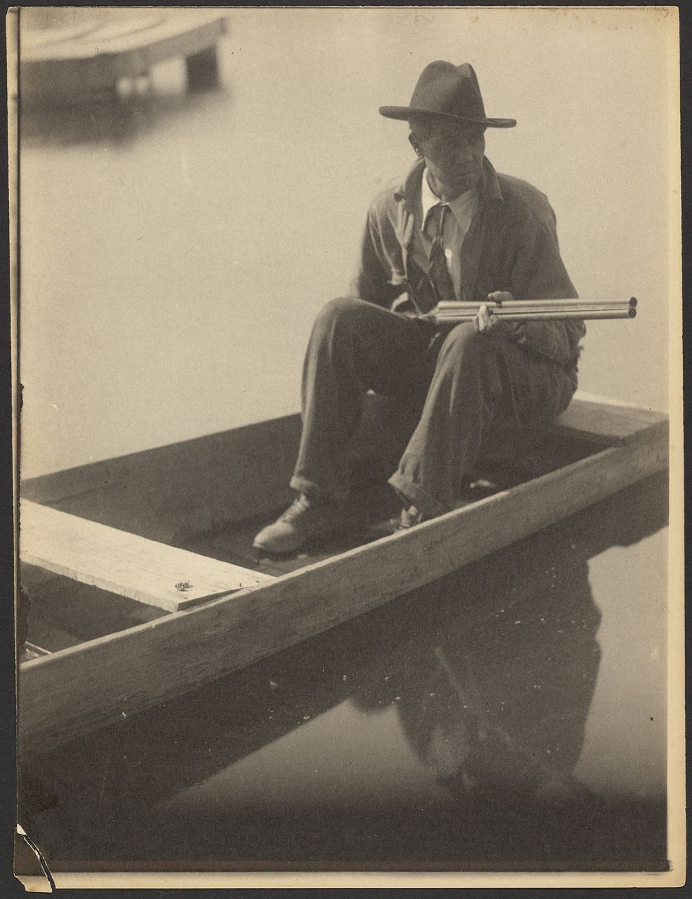 Black Man in Flat Boat, Holding Shotgun by Doris Ulmann