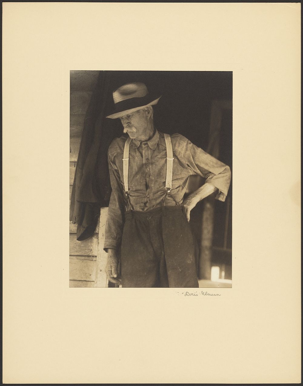 Mustached Old Man with Straw Hat and Suspenders Standing in Doorway by Doris Ulmann
