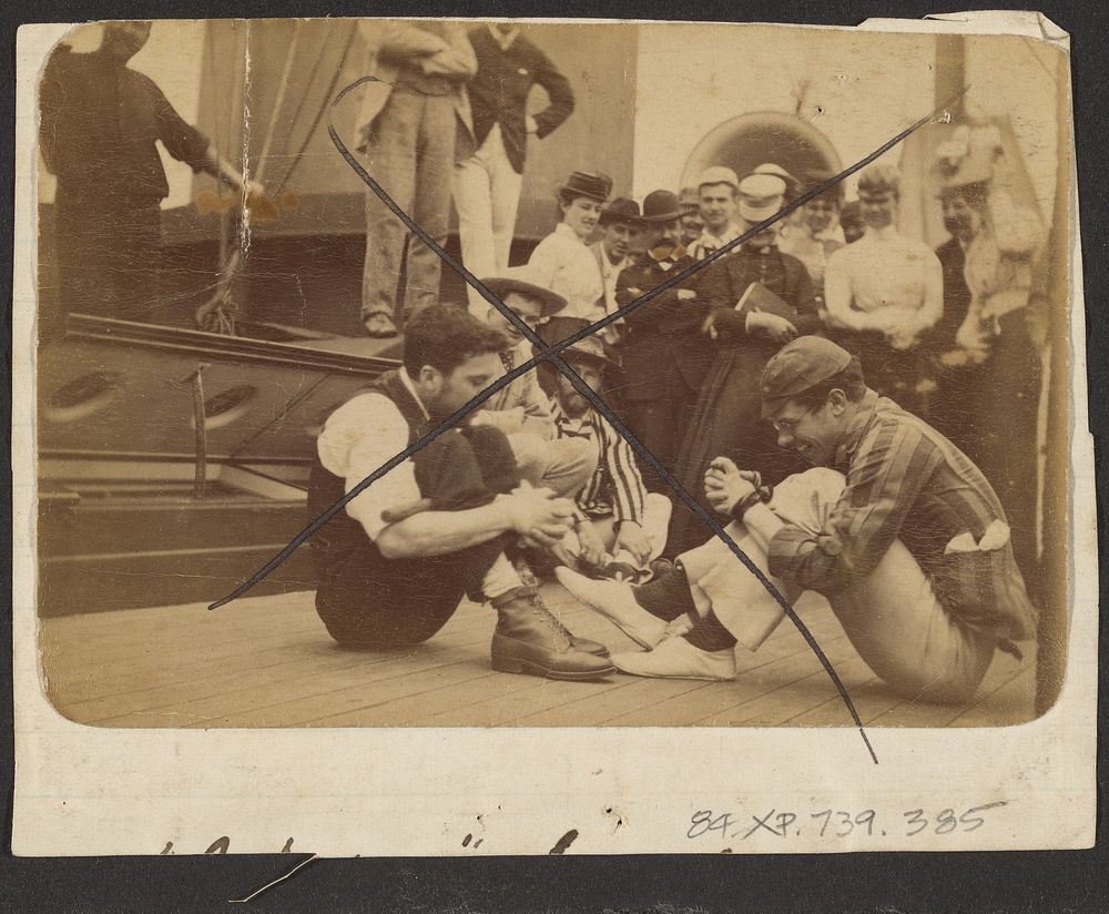 Two men with hands bound on deck of ship