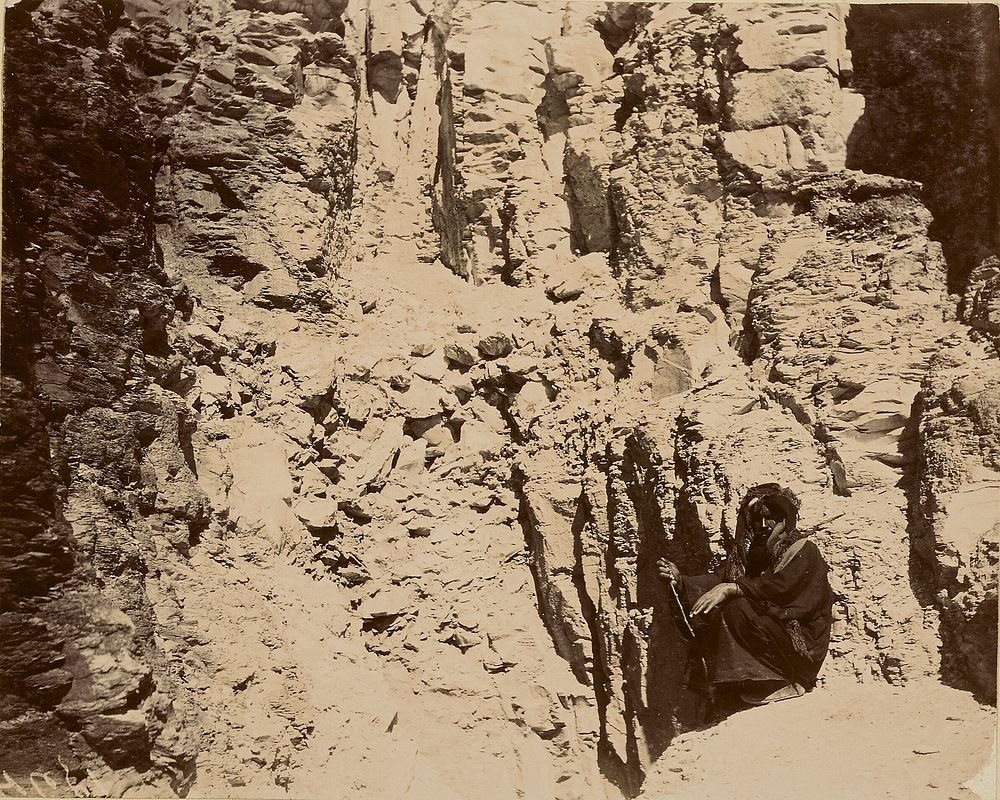 Man sitting at base of cliff wall