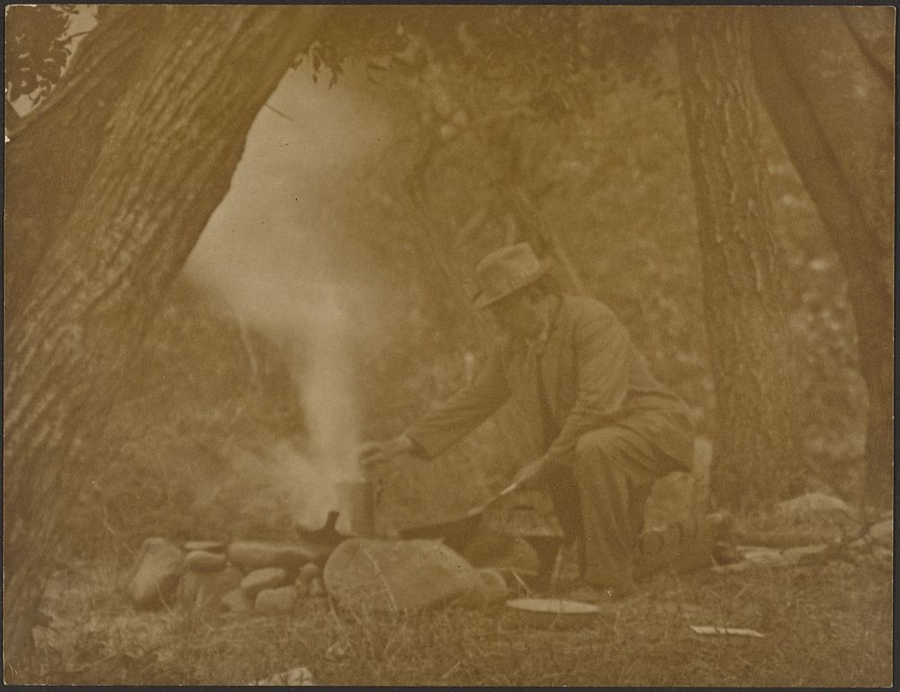 Man Cooking on Camping Fire in Woods by Louis Fleckenstein