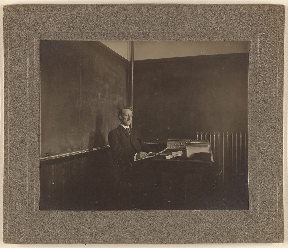 Portrait of a male teacher seated at his classroom desk