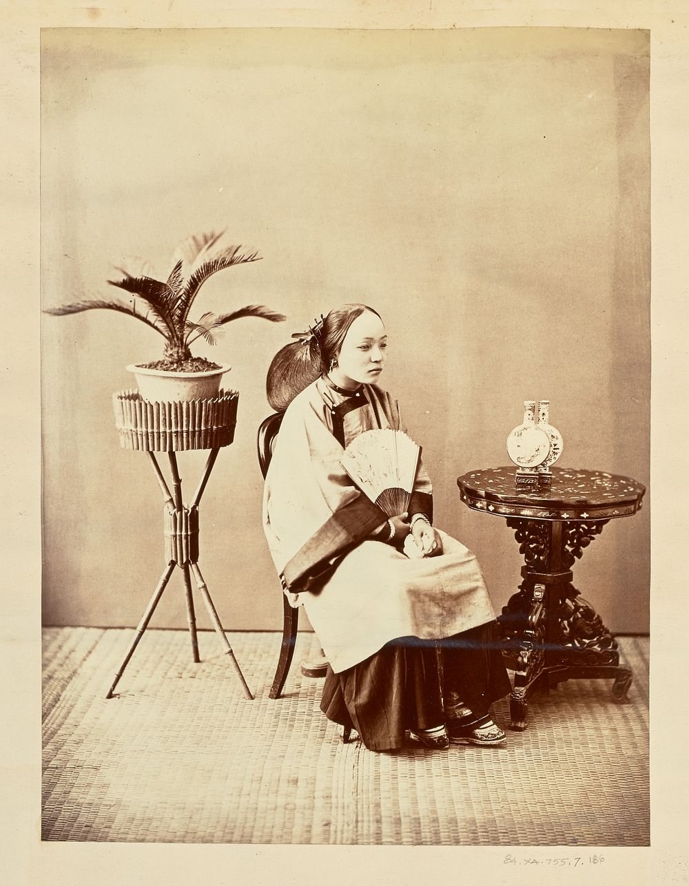 Studio portrait of a seated young woman holding a fan by William Saunders