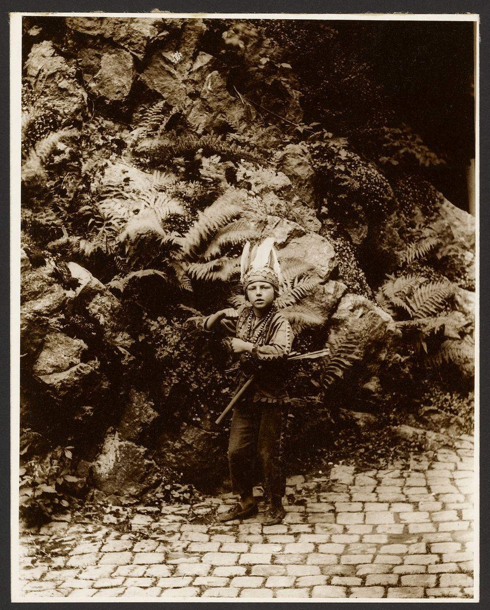 Boy Dressed as an Indian Posed in Front of Ferns by Alphonse Maria Mucha