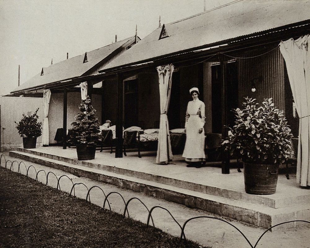 An isolation hospital, Nottingham: a nurse stands by beds on the verandah of a hospital ward. Photograph, 1890/1910.