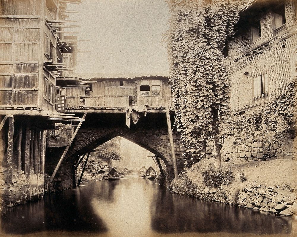 Kashmir: a built-over bridge on a canal betweeen houses. Photograph by Samuel Bourne.