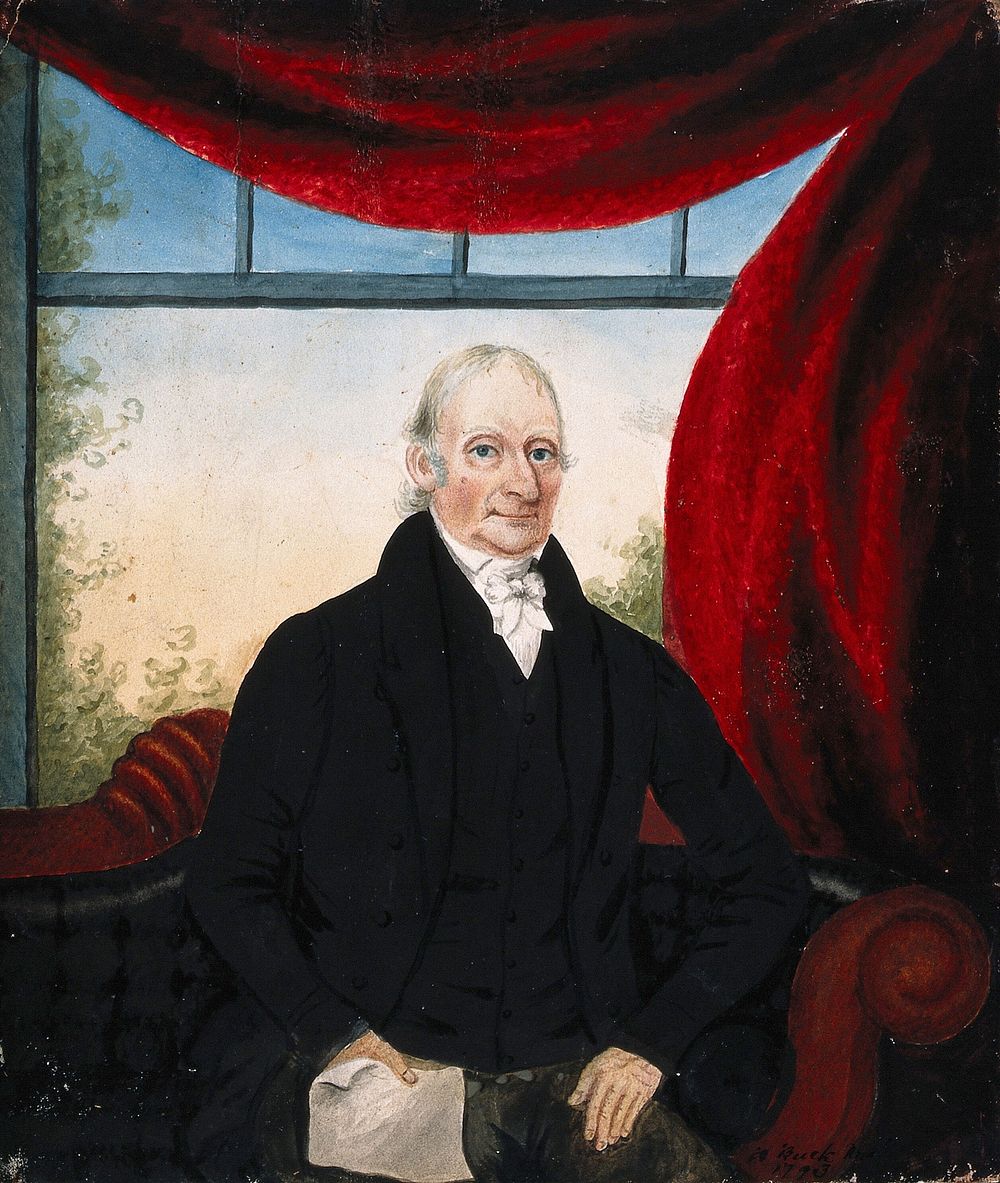 A member of the Jenner family , seated on a sofa, holding a paper in his right hand; behind, a window framed with a red…
