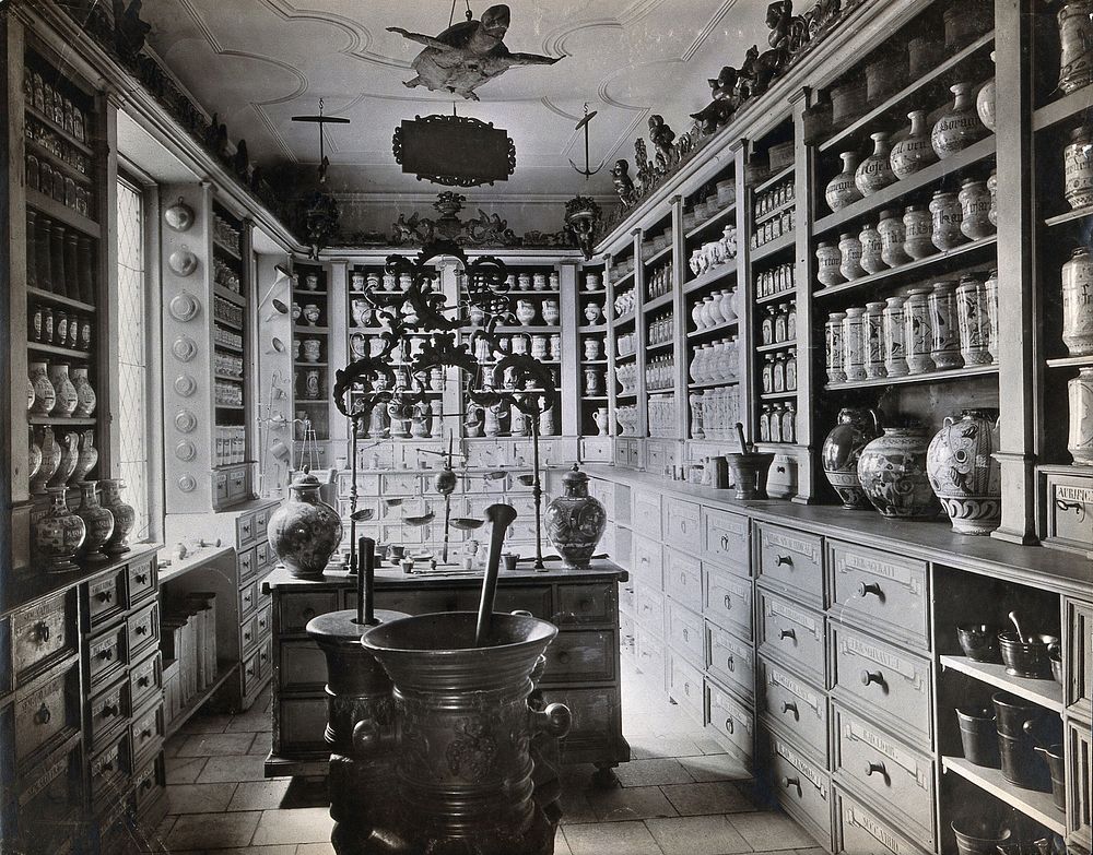 A seventeenth-century German apothecary's shop with ornate pharmacy jars, large metal mortars and a stuffed turtle hanging…