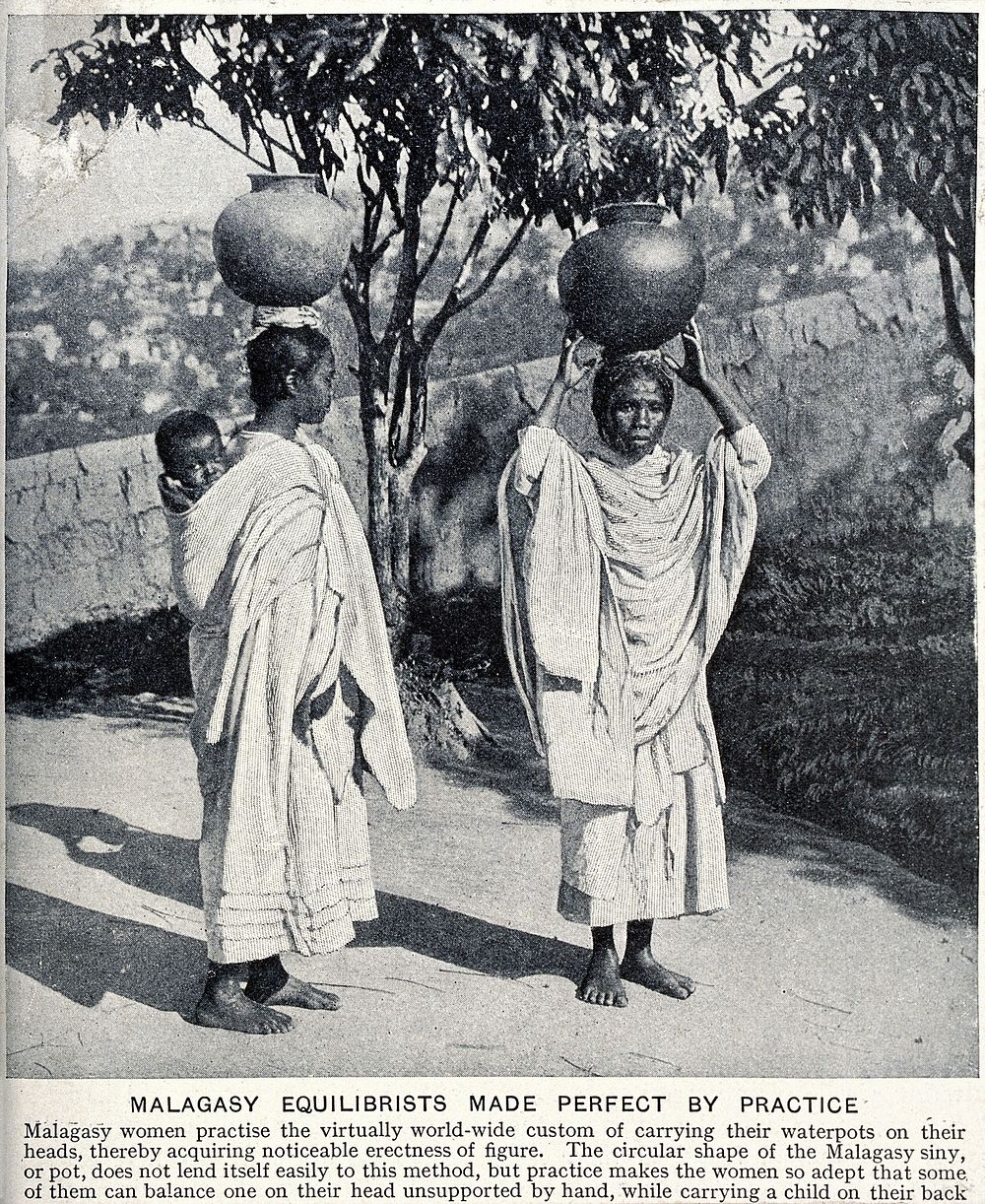 Two Malagasy women carrying waterpots on their heads; the woman on the left also carries a child on her back. Halftone.