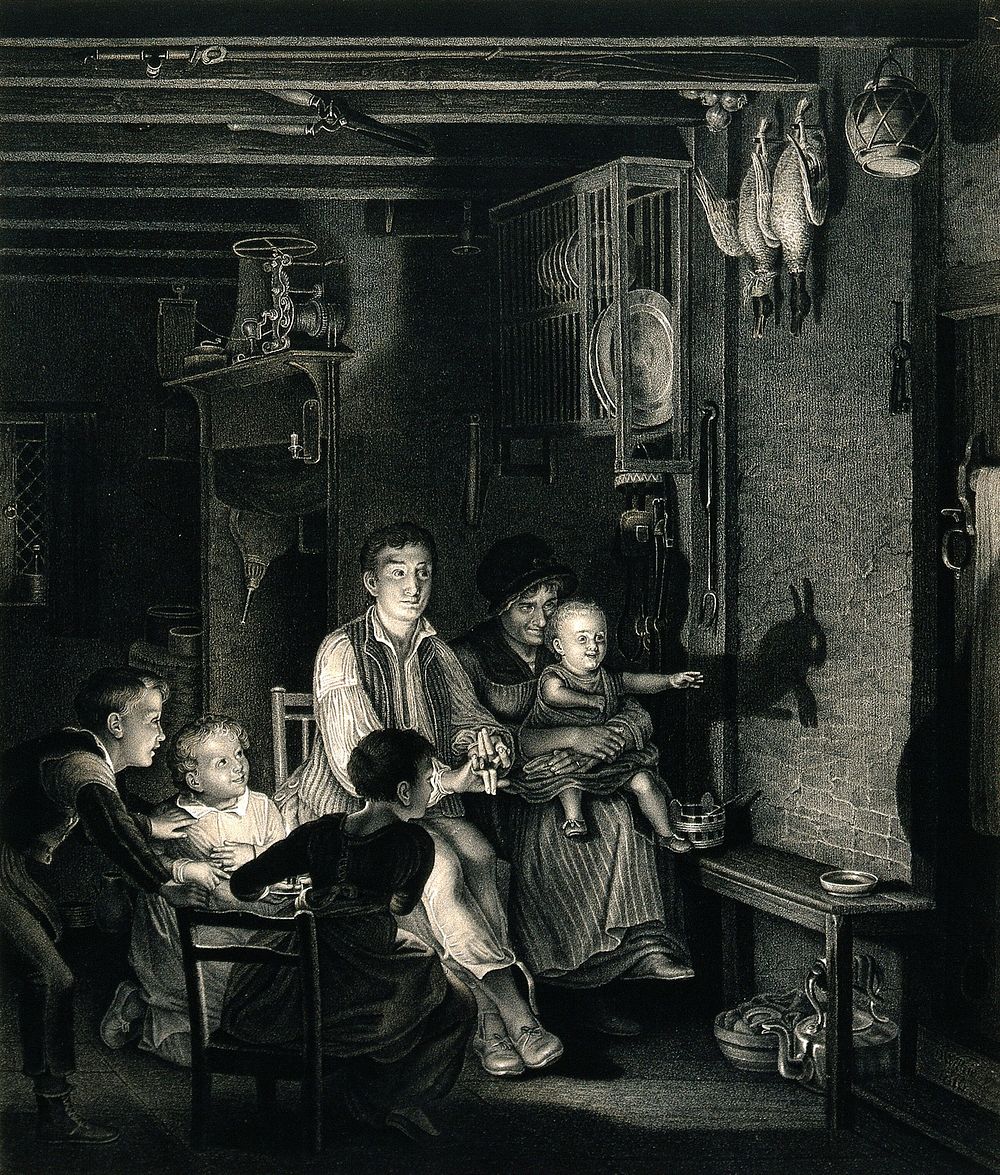 A family sit together in the darkened kitchen where the children are amused by their father making animal shadows in the…