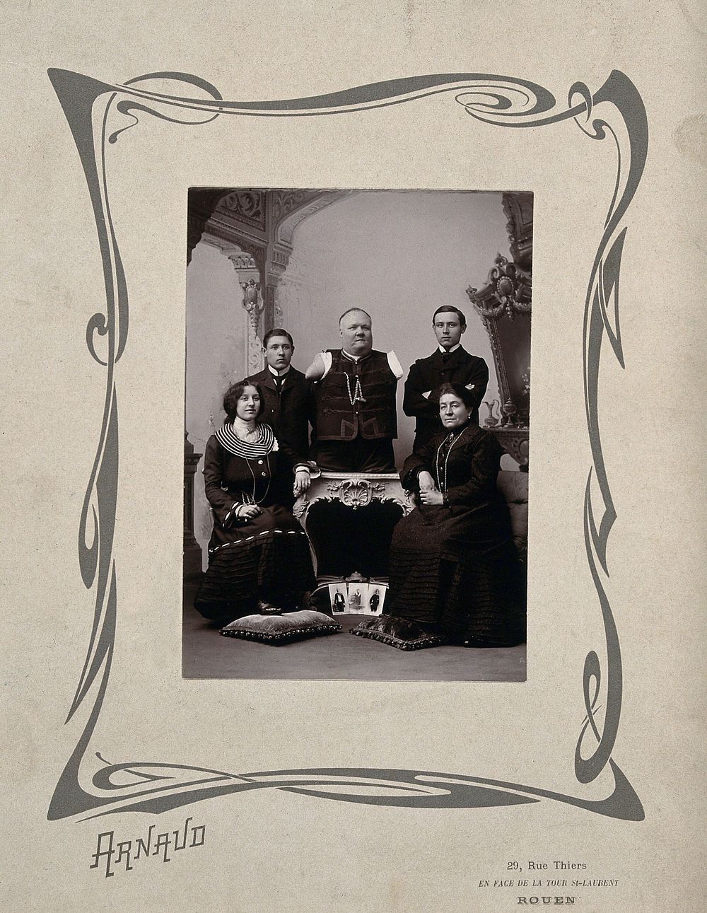 A family portrait: a man without arms and legs poses on a table surrounded by family.