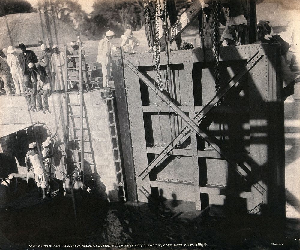 Menufia Canal, Egypt: reconstruction work to the first Aswan Dam: men at work lowering a flood gate. Photograph by F.…
