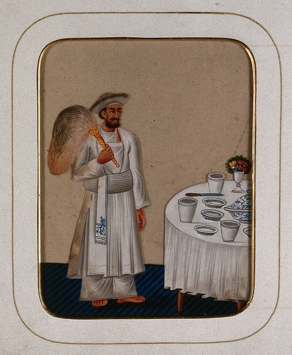 A servant standing next to a dining table, holding a fly whisk. Gouache painting on mica by an Indian artist.