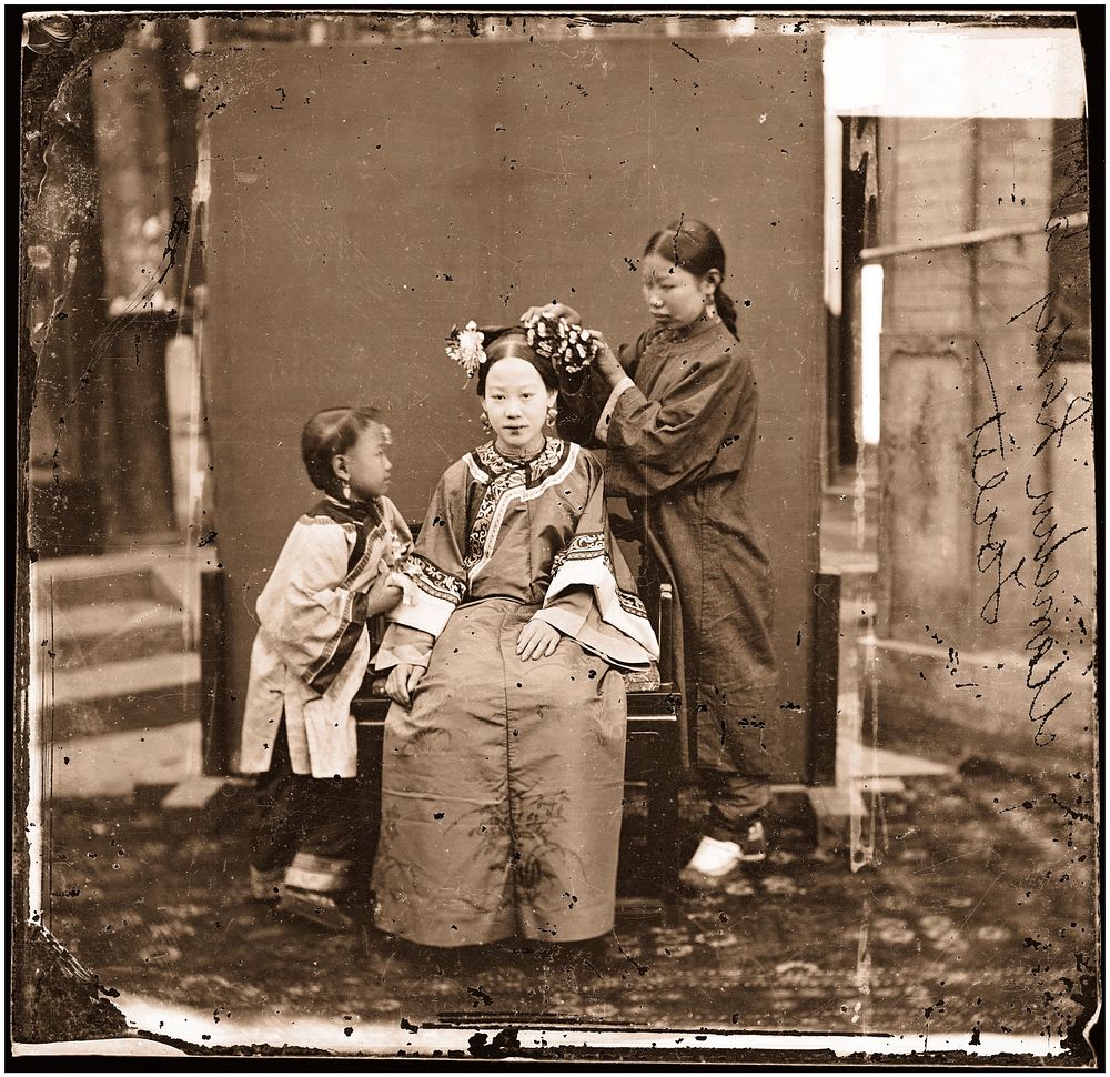 China: a Manchu lady having her hair dressed by her servant girl, Beijing. Photograph by John Thomson, 1869.