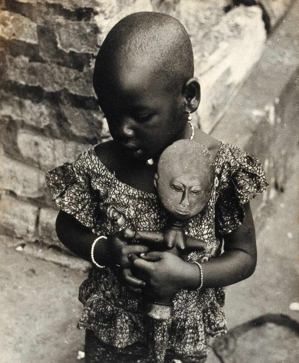 Ghana: a child holding an Akuaba doll. Photograph by H.V. Meyerowitz, 19--.