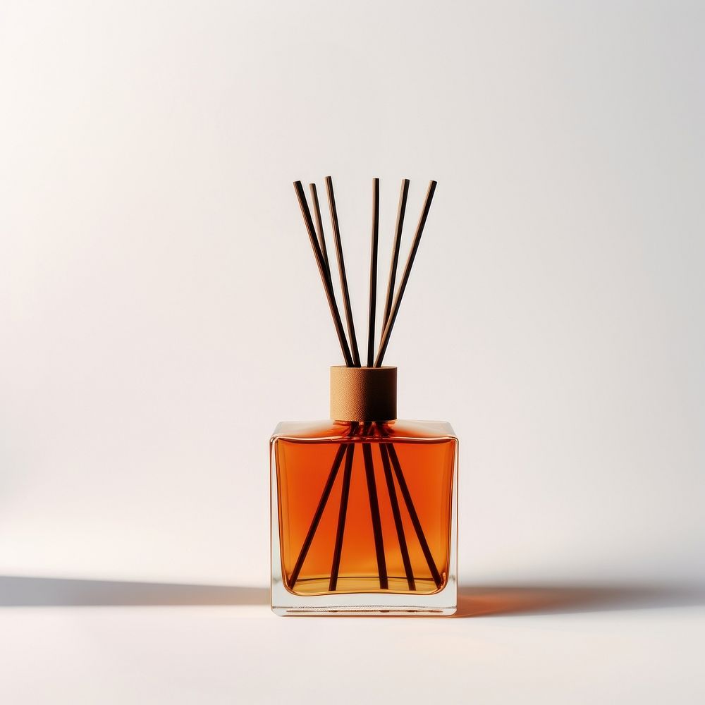 A burnt orange glass reed diffuser bottle cosmetics perfume white background.