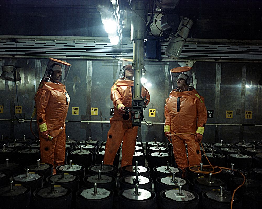 Maintenance workers dressed in supplied airsuits working on the x4 retriever system in building 707.