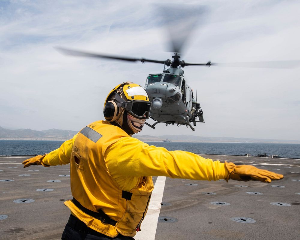 Boatswain’s Mate 2nd Class Anthony Zungri, from Brick Township, N.J., signals to the pilot of a UH-1Y Venom during flight…