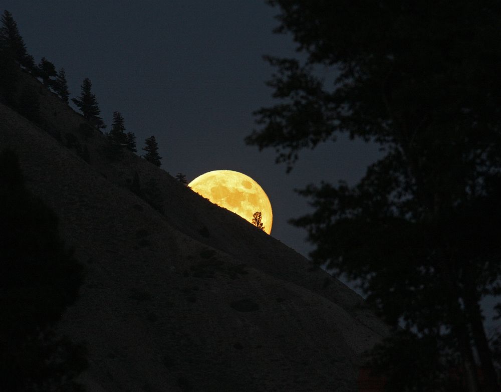 Yellow moon peeking out from mountain. Original public domain image from Flickr