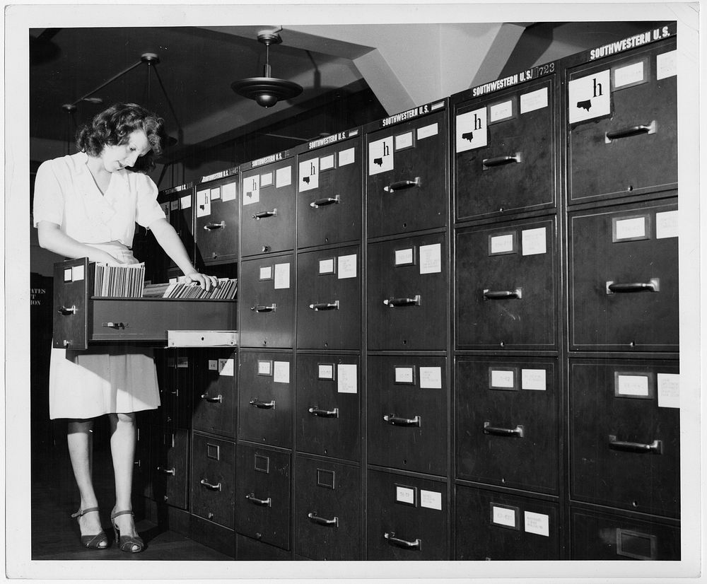 Jeannette Poirier looking at photographs in file cabinet drawer at the Washington office of the Overseas Branch of the U.S.…