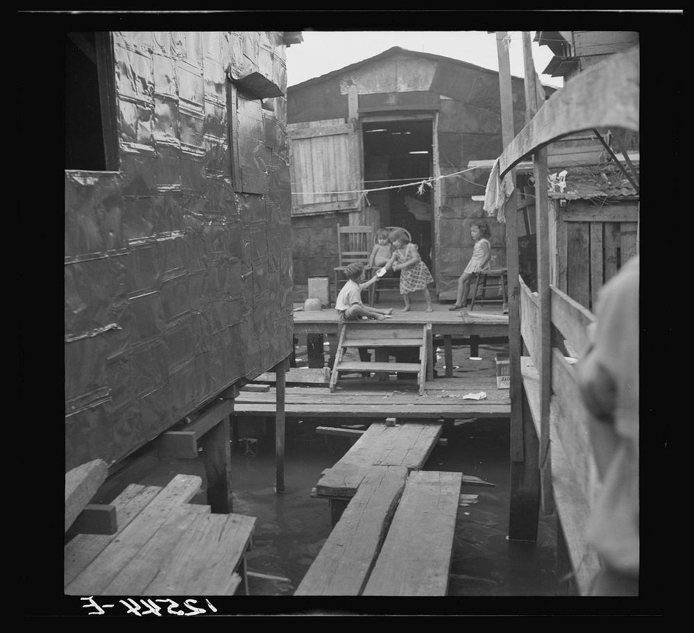 Children in the workers' quarter of Puerto de Tierra. Note the water of the tidal swamp under the houses and "sidewalk." San…