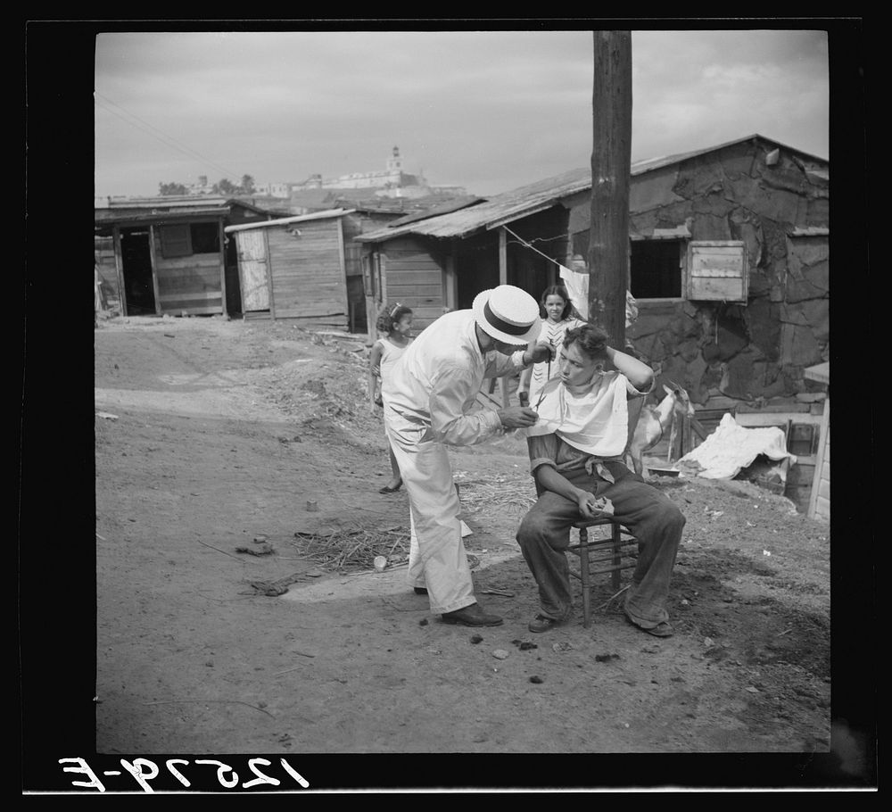 Itinerant barber at work in the worker's quarter of La Perla. San Juan, Puerto Rico. Sourced from the Library of Congress.