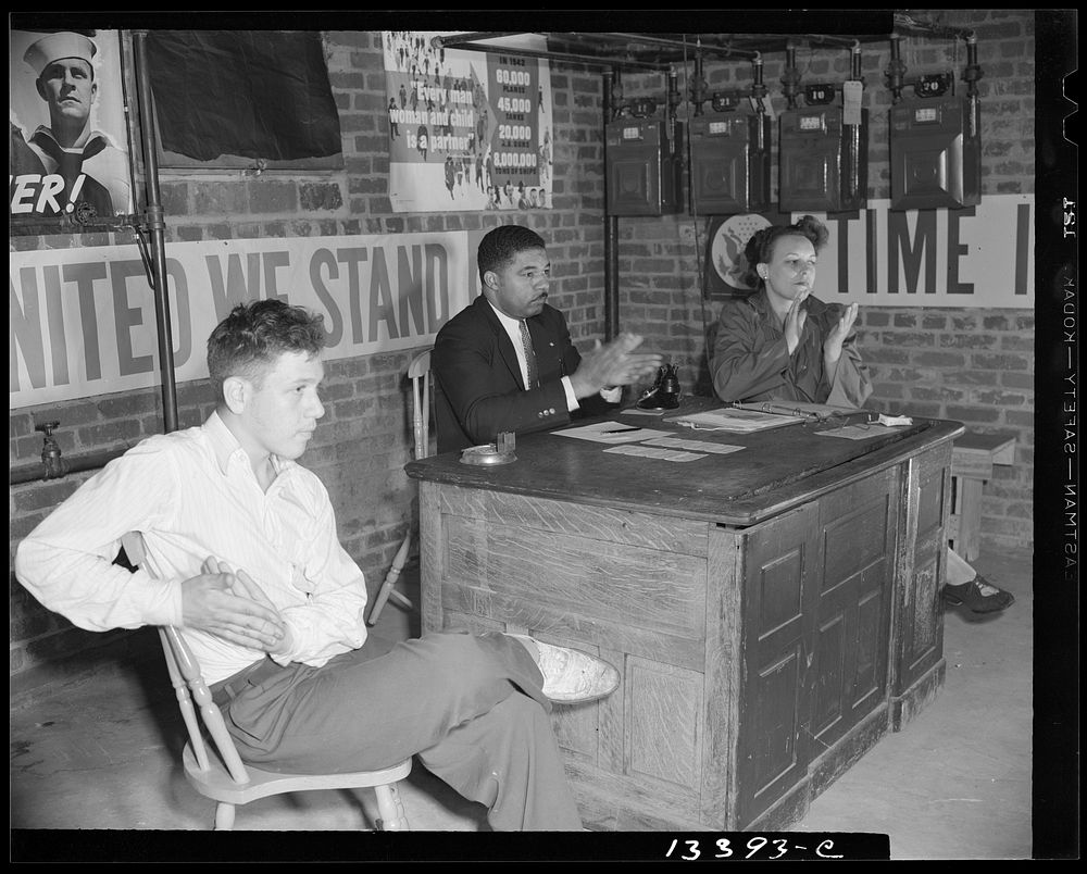 Washington, D.C. Air raid wardens' meeting in zone nine, Southwest area. Chairman, secretary and a messenger applauding a…